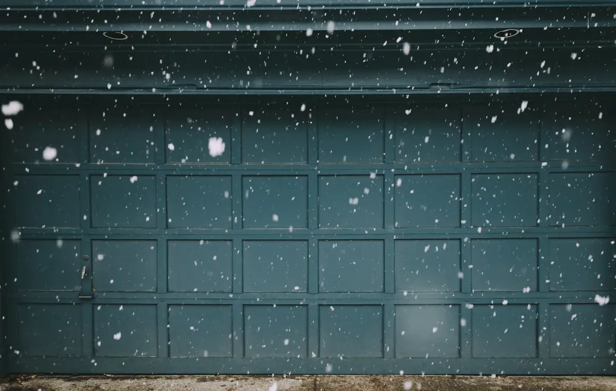 A closed garage door with snow falling in front of it