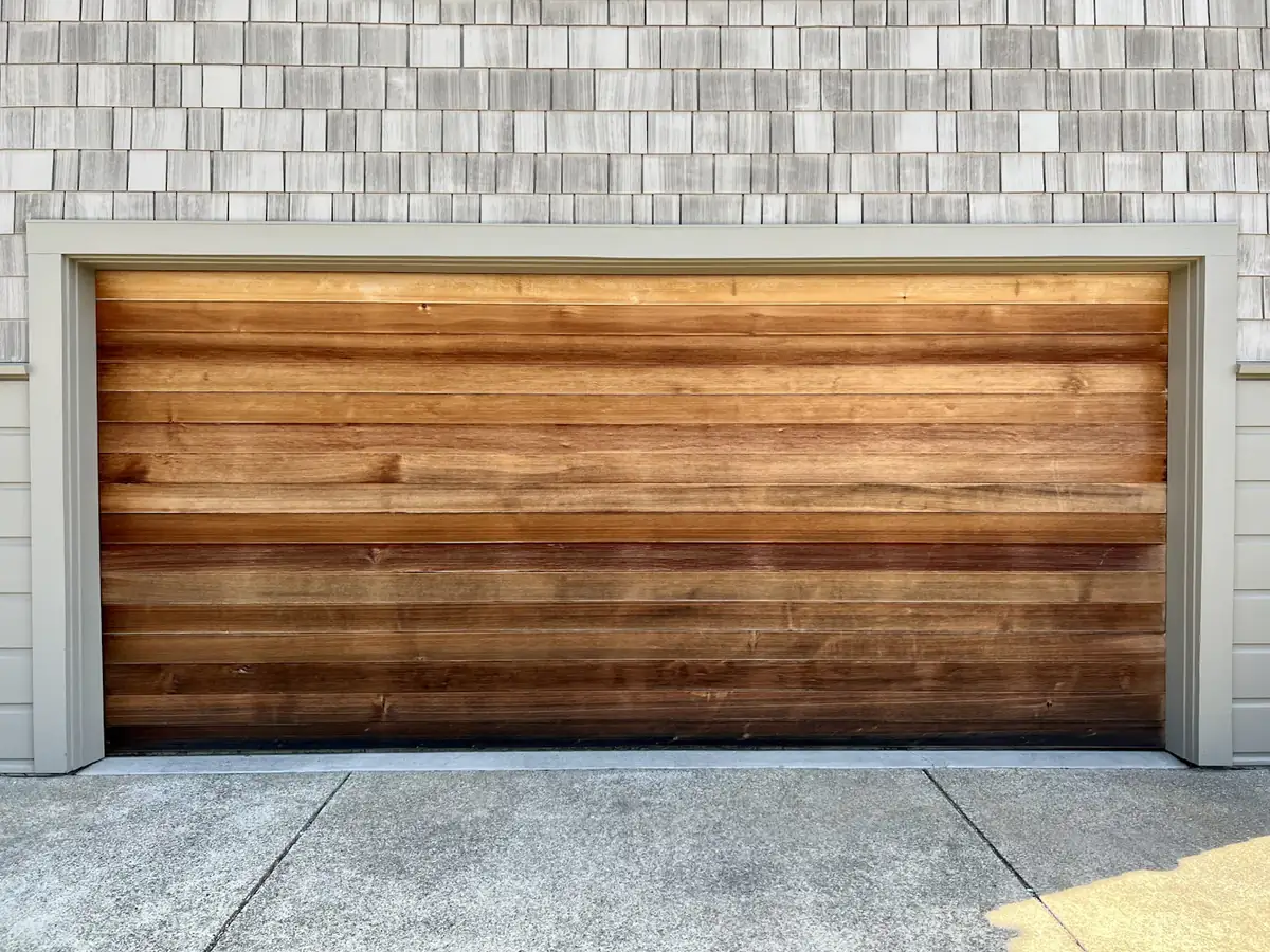 A wooden garage door set into a brick wall